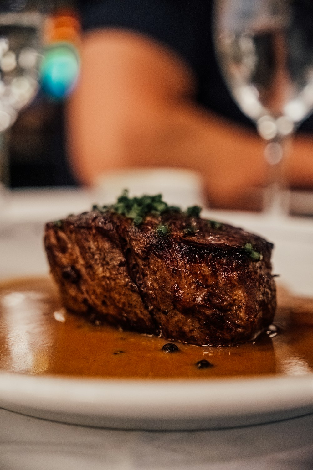 a piece of steak on a plate with sauce and garnish