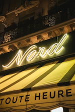 Nighttime exterior of L'Or Noir nightclub with glowing black and gold signage.
