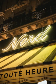 Nighttime exterior of L'Or Noir nightclub with glowing black and gold signage.