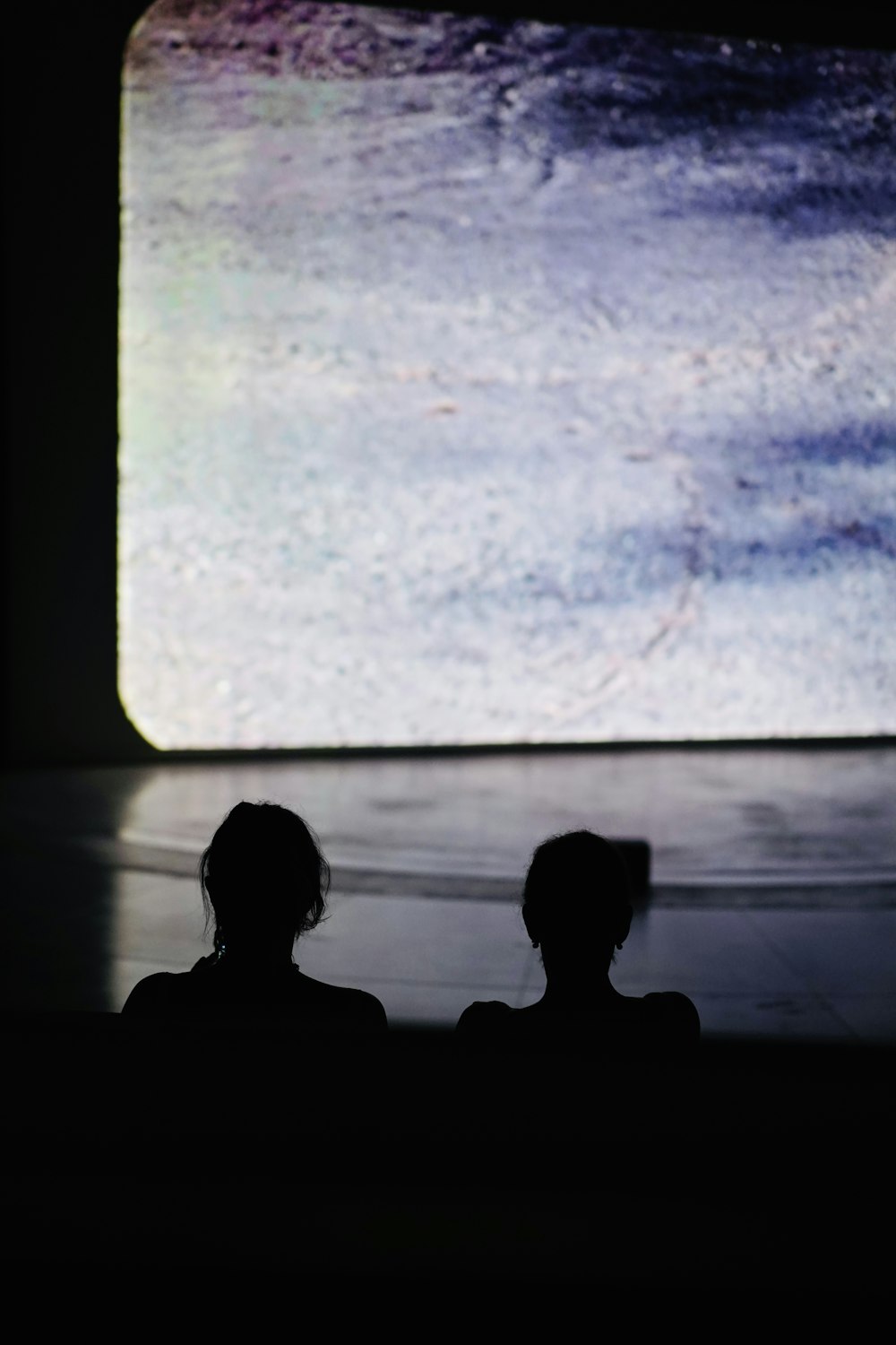 two people sitting in front of a large screen