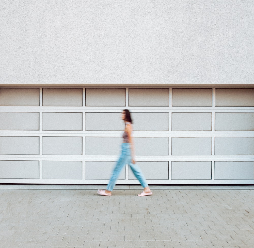 a woman walking in front of a garage door