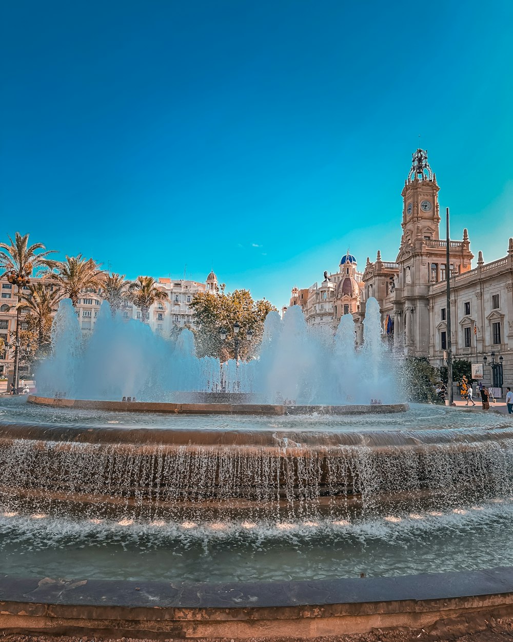 a water fountain in front of a building with a clock tower