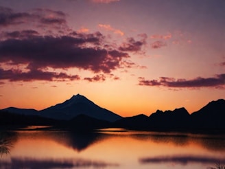 A serene landscape showcasing mountains and a tranquil lake at sunset.