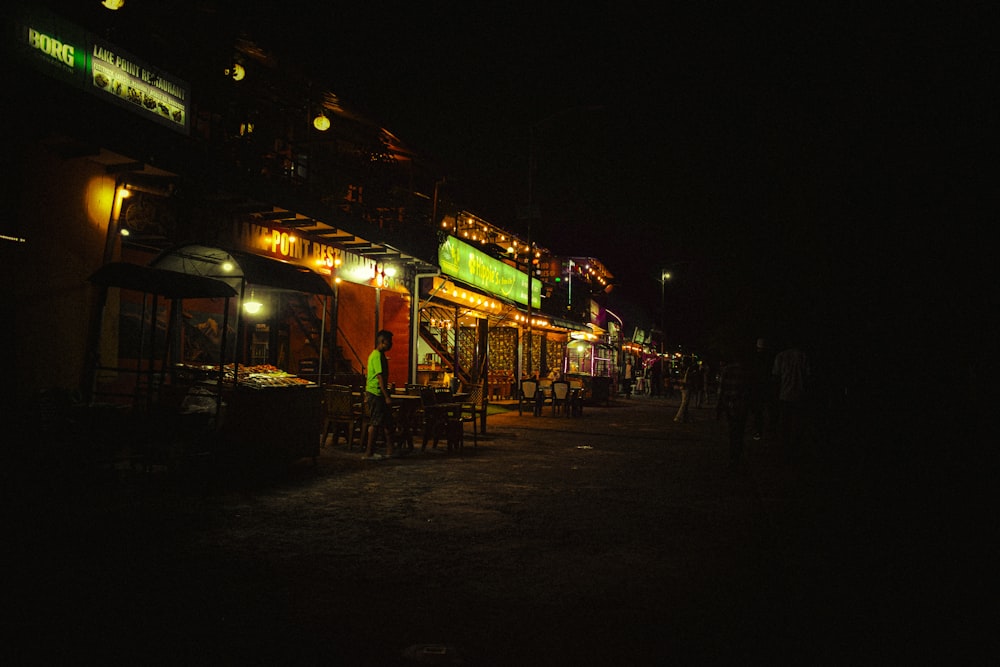 a dark street at night with a restaurant lit up