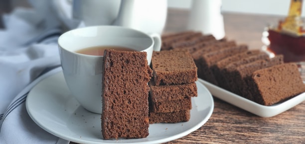 A happy customer enjoying a slice of bread with a cup of tea in a cozy kitchen setting.