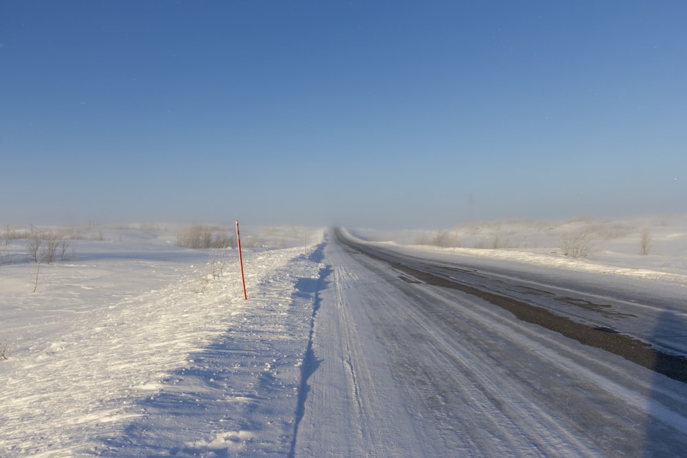 a snow covered road in the middle of a field