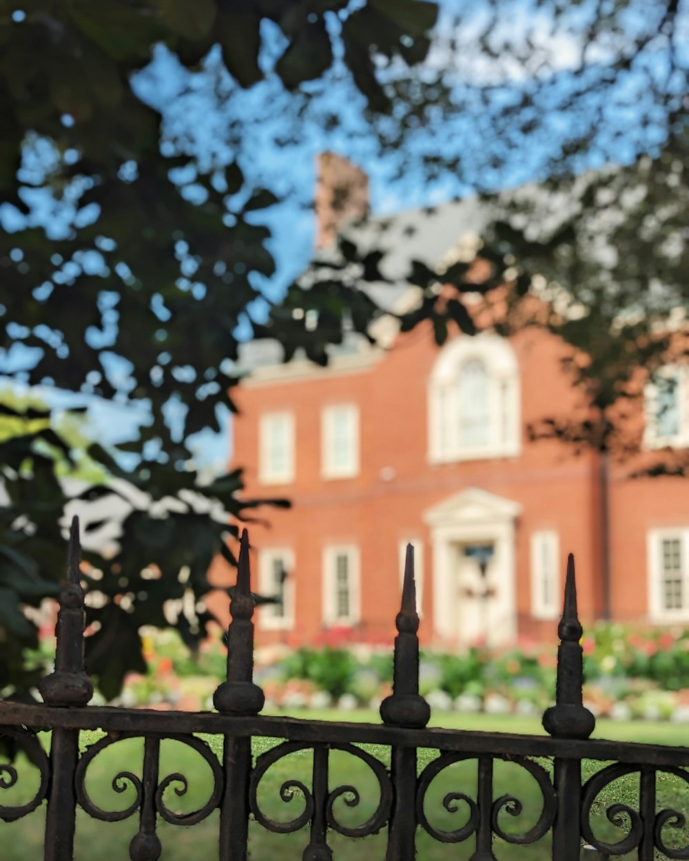 a red building behind a fence with a clock on it