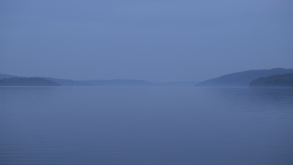 a large body of water with hills in the distance