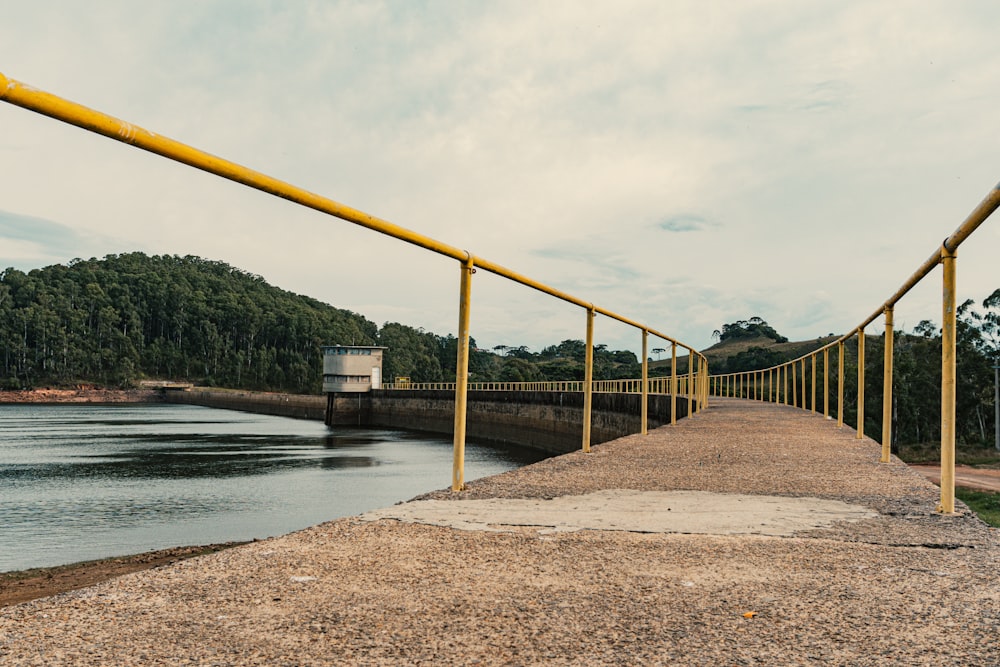 a long yellow railing next to a body of water