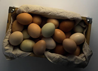 A basket filled with warm brown and cream-colored eggs resting on rustic wooden boards.