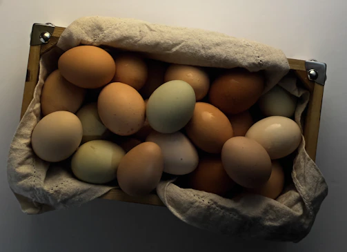 A basket filled with warm brown and cream-colored eggs resting on rustic wooden boards.
