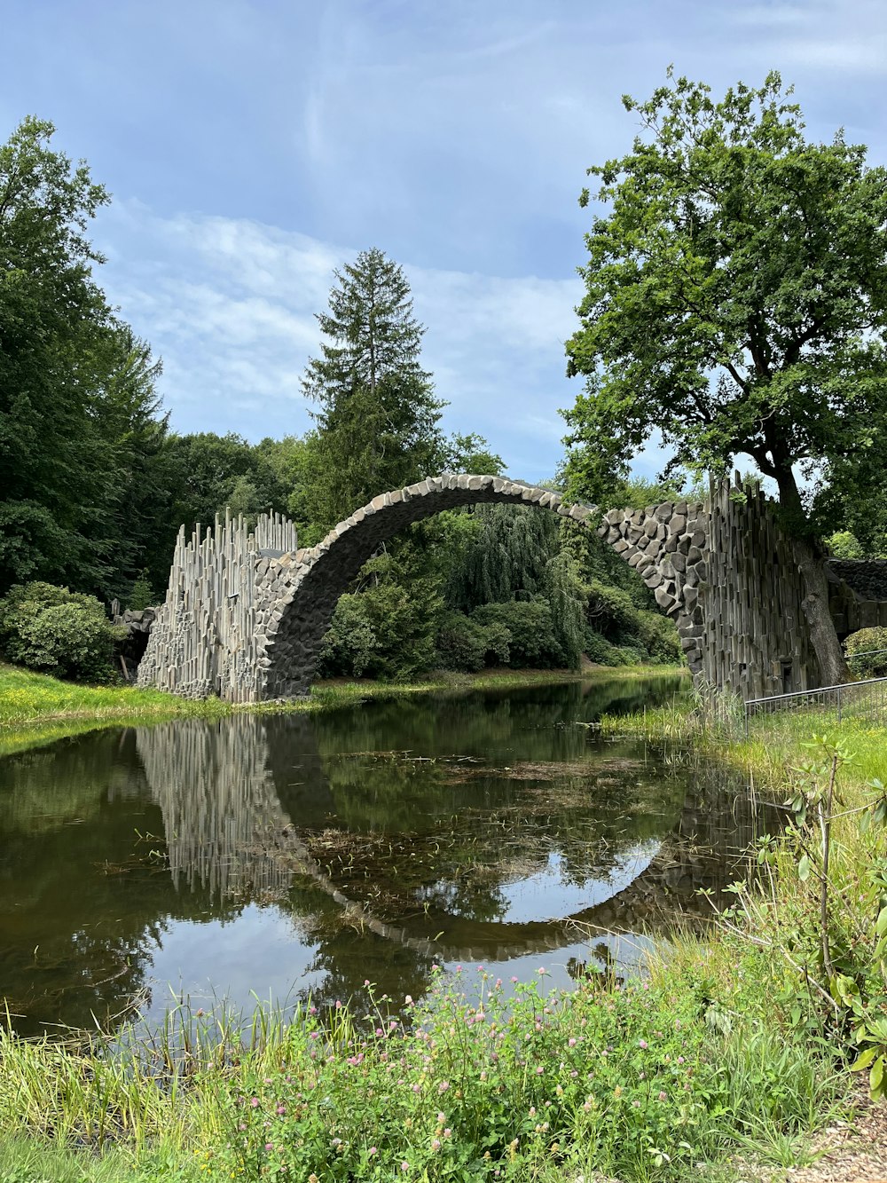 a stone bridge over a pond in a park