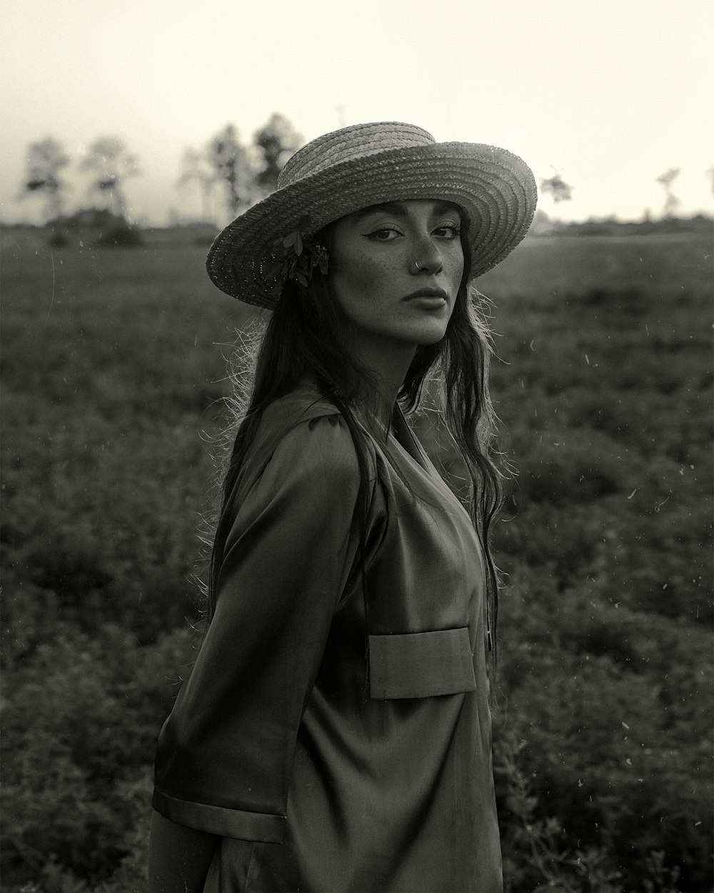 a woman wearing a hat standing in a field