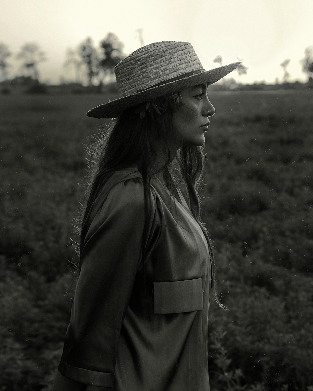 a woman standing in a field wearing a hat