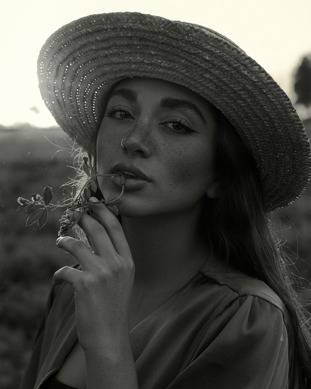 a woman in a straw hat holding a flower