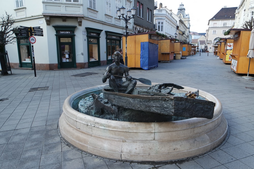 a statue of a man sitting on top of a fountain