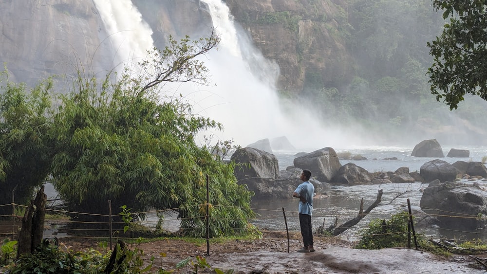 Un uomo in piedi davanti a una cascata