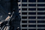 A detailed sculpture of historical figures stands prominently with a backdrop of a modern, high-rise building featuring a grid of dark windows.