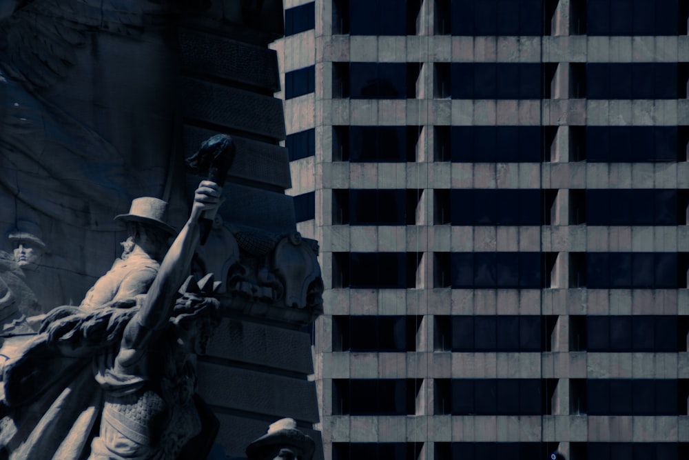 a statue of a man holding a baseball bat in front of a tall building