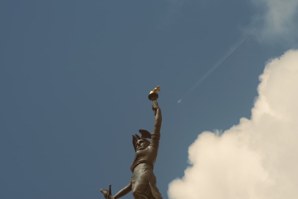 a statue of a woman reaching up into the sky