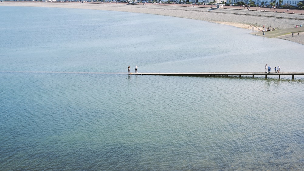 a group of people standing on a pier in the middle of a body of water