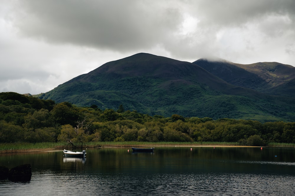 a boat floating on top of a lake next to a mountain