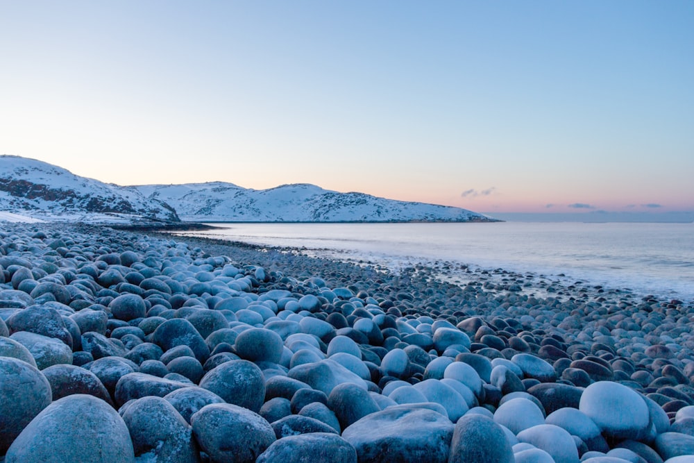 a beach covered in lots of rocks next to the ocean