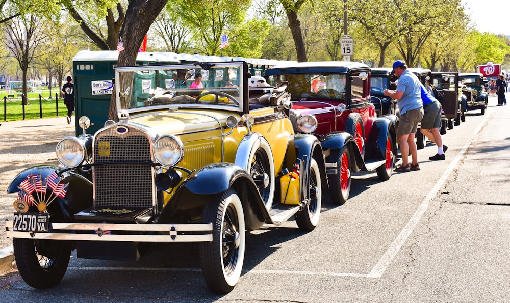a row of antique cars parked on the side of a road