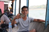 Fisherman enjoying a refreshing drink on a boat with jungle backdrop during a tour.