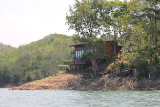 A handcrafted wooden home with large windows capturing the serene Kashmiri landscape.
