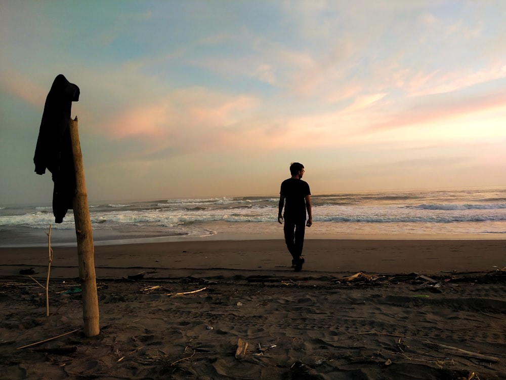 um homem em cima de uma praia de areia ao lado do oceano