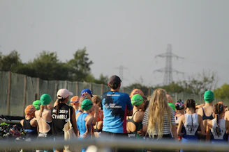 A diverse group of athletes training together outdoors, showcasing swimming, cycling, and running in action.
