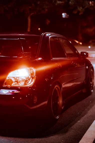 A sleek black car with custom red LED interior lighting glowing vividly at night.