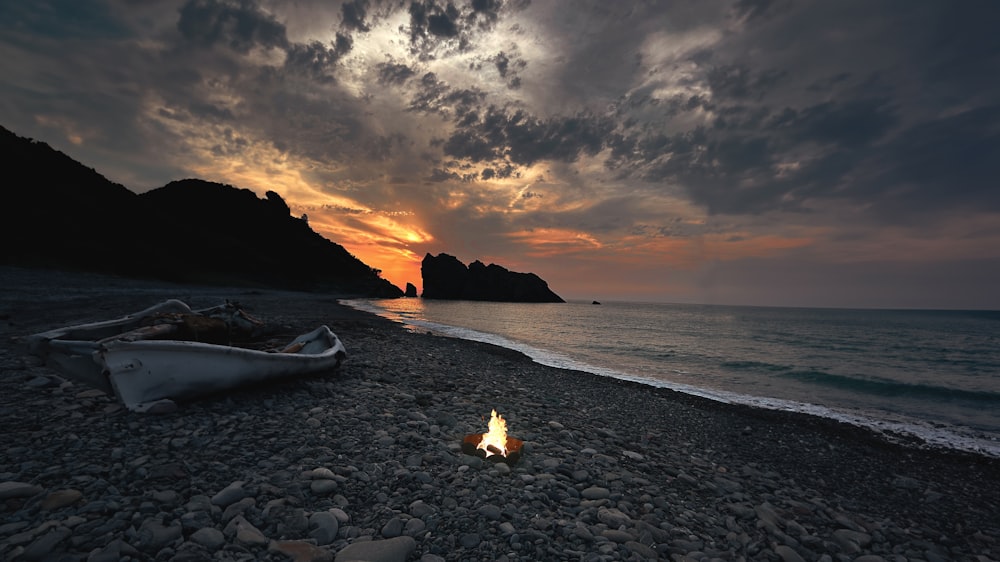 a boat sitting on top of a beach next to the ocean