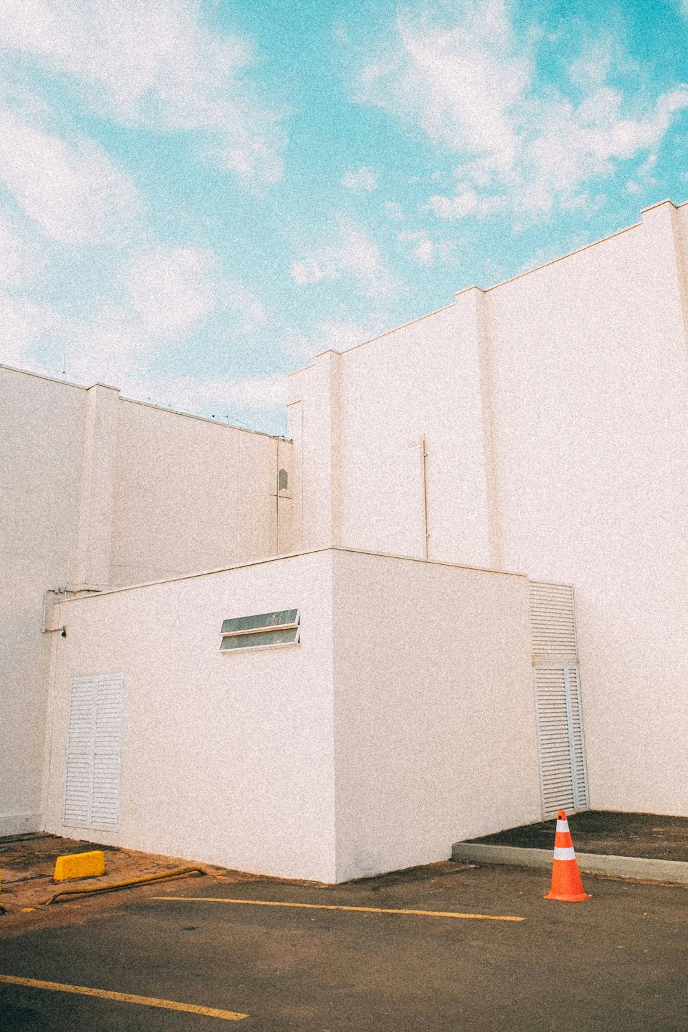 a parking lot with a white building and orange cones