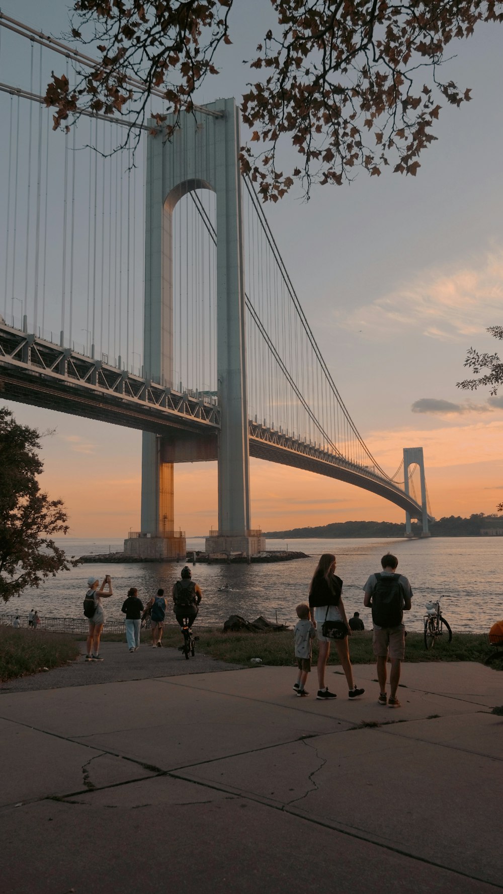 a group of people standing next to a river under a bridge