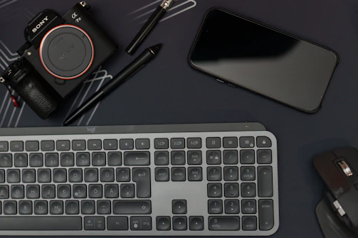 Abstract shot of tech devices and content creation tools arranged on a dark, polished surface.