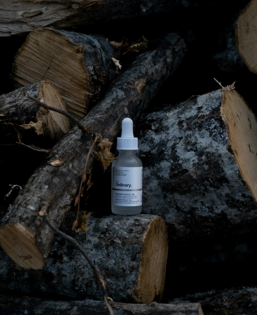 a bottle of liquid sitting on top of a pile of logs