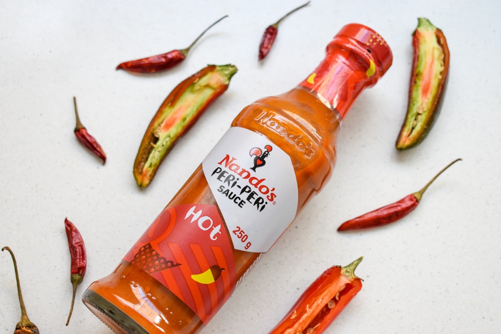 a bottle of hot sauce surrounded by hot peppers