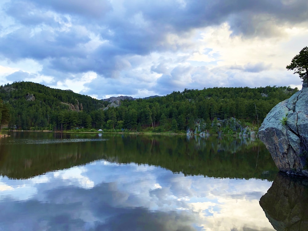 a lake surrounded by trees and a large rock