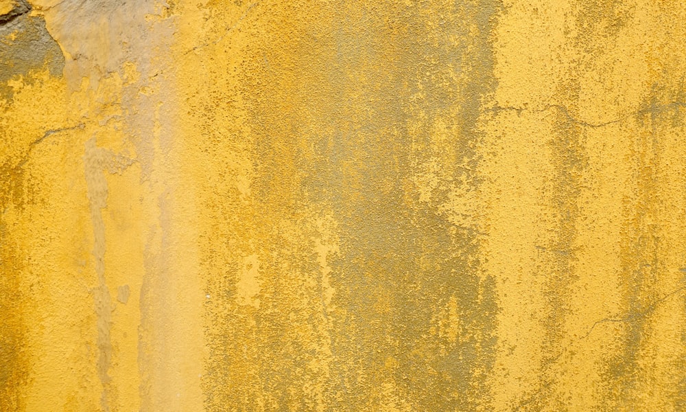 a yellow painted wall with peeling paint on it