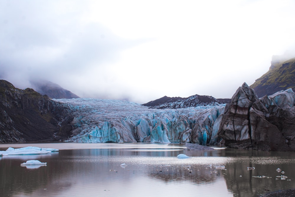 a group of icebergs floating in a lake surrounded by mountains