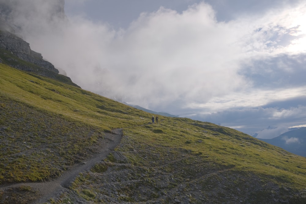 a person walking up a grassy hill on a cloudy day