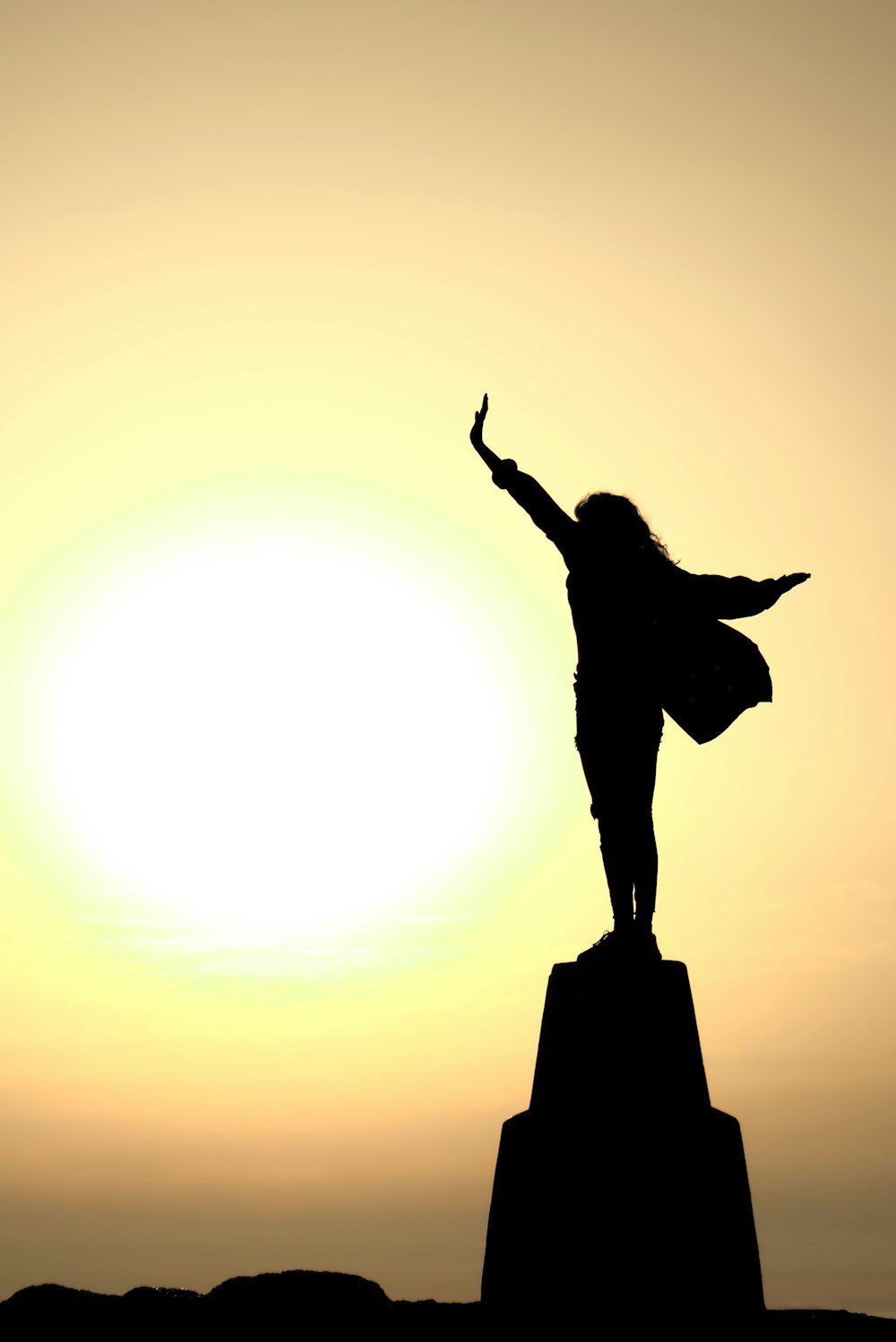 a woman standing on top of a rock with her arms in the air