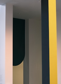 A minimalist design featuring vertical strips and shapes in different colors, including yellow, dark green, and beige. The design has a modern and abstract feel.