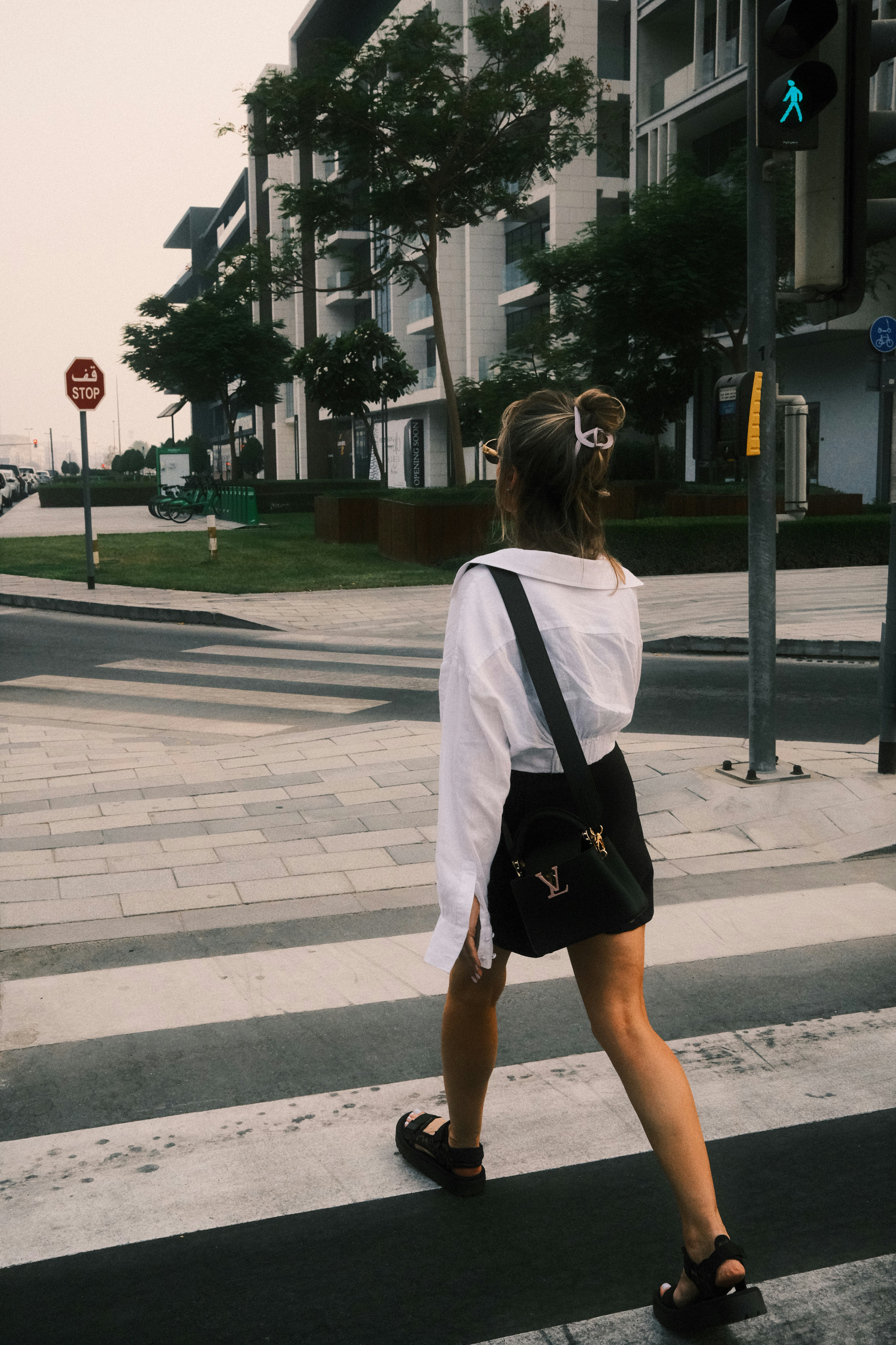 a woman walking across a street holding onto a crosswalk