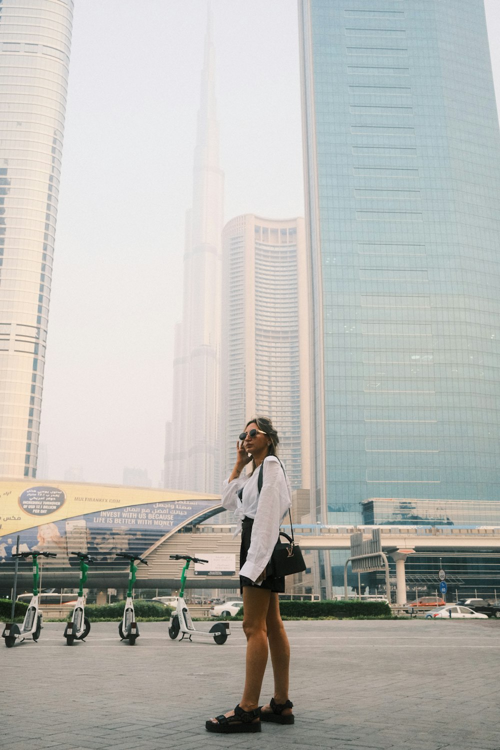 a woman standing in front of a tall building talking on a cell phone