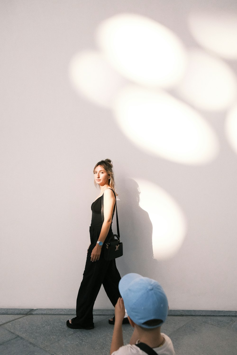 a woman standing next to a white wall