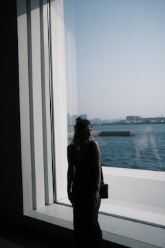 A calm leader standing thoughtfully by a window overlooking a cityscape at dawn, embodying quiet strength.