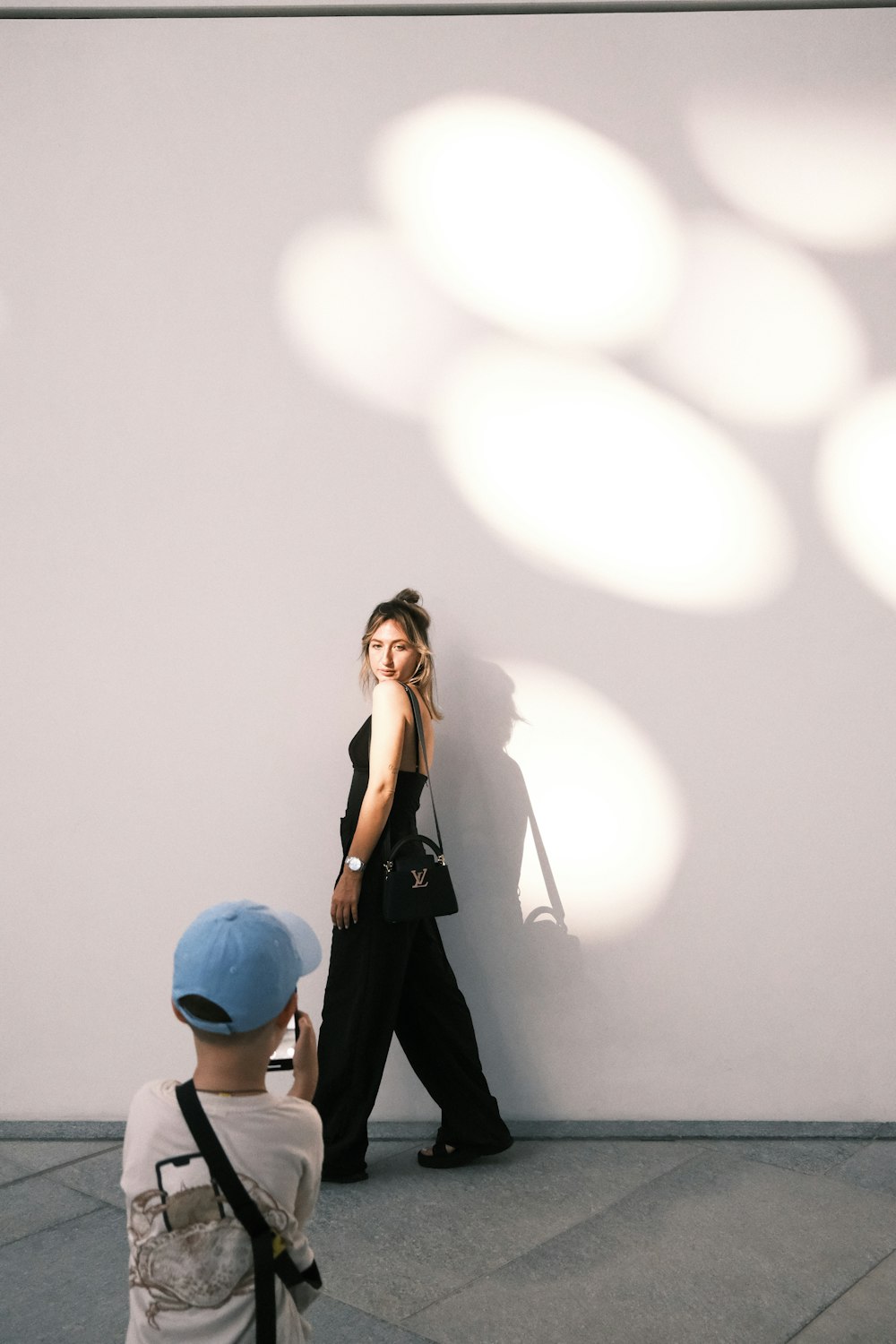 a woman standing next to a white wall talking on a cell phone